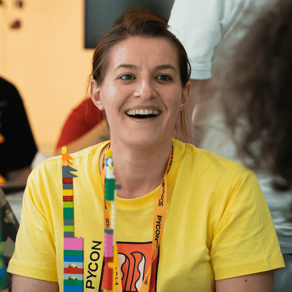 ellow t-shirt and engaging with other attendees while seated at a table filled with colorful Lego pieces.